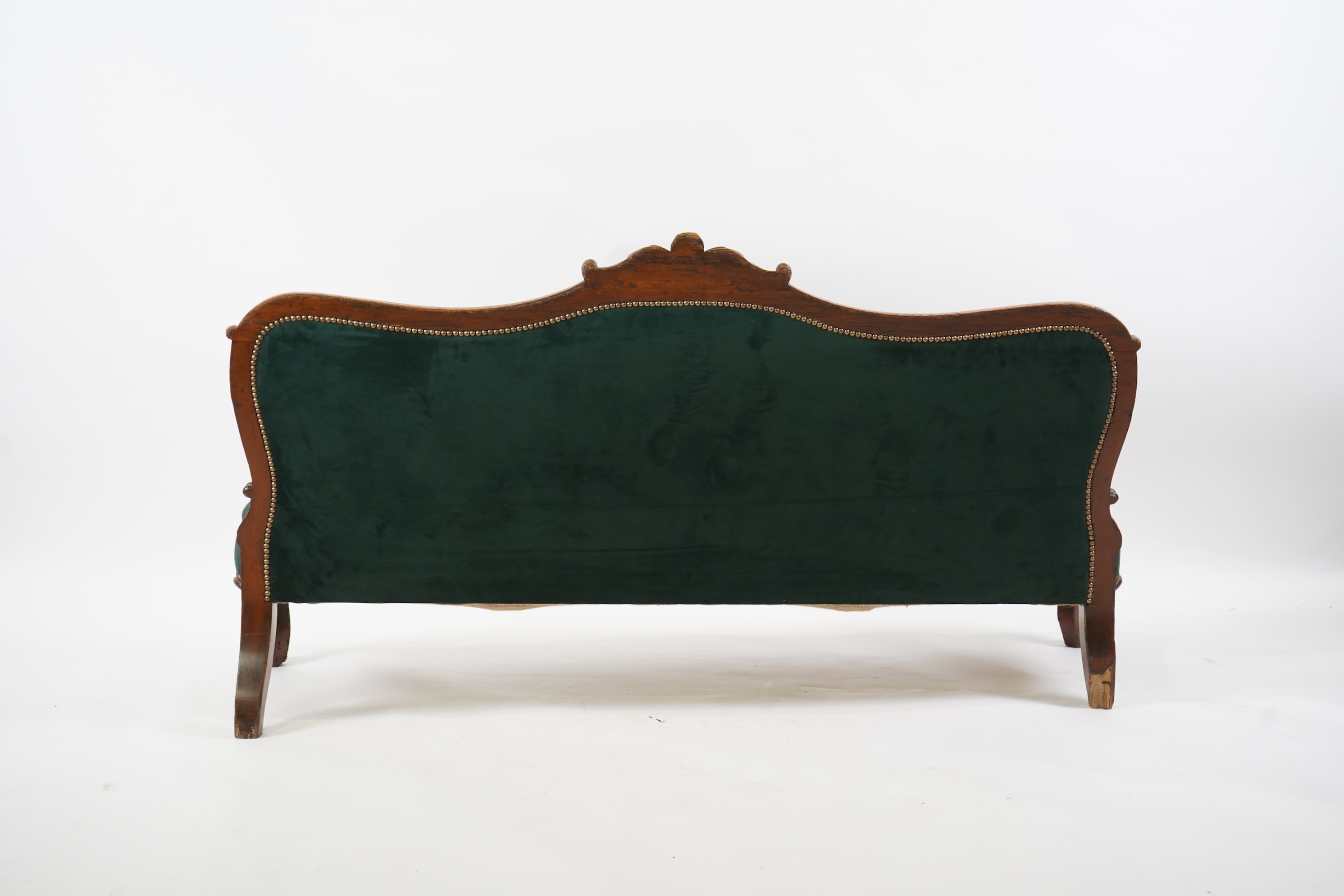 A pair of Victorian carved oak settees, recently re-upholstered in deep buttoned green velvet, the scroll carved crest rails over serpentine seats on cabriole front legs, 160cm wide, 96cm high, Provenance - previously gi